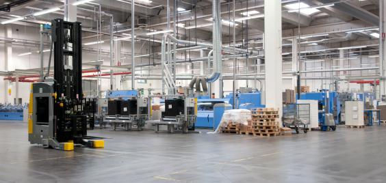 industriebouw-vorkheftruck Een vorkheftruck die door een loods met machines rijdt over een gladde vloer.