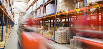 magazijnen_met_stellingen Een magazijn waar palletwagens rijden over een gladde vloer.